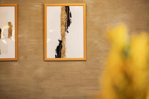 two framed pictures on a wall with yellow flowers at Holiday cottage BEPPU ICHIYA in Beppu