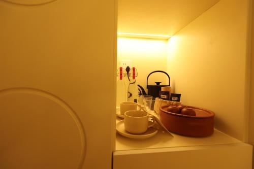 Un estante con tazas y un bol de fruta encima. en 大胡子民宿, en Shantou