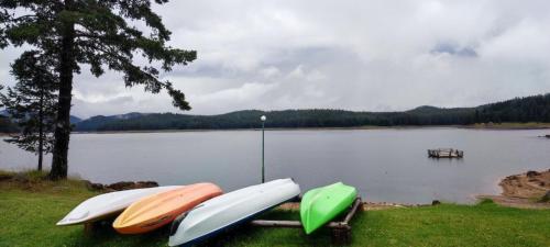 three boats sitting on the grass near a lake at Romantica Forest Guest House in Dospat