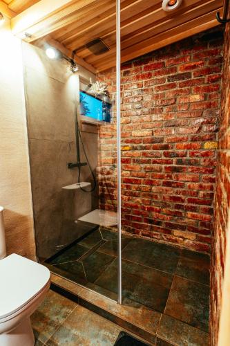 a bathroom with a glass shower in front of a brick wall at Hercogi in Ābeļi