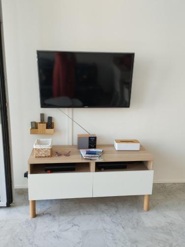 un salon avec une télévision sur un mur blanc dans l'établissement Appartement Terrasse, centre-ville, 5 min de la plage, à Cavalaire-sur-Mer