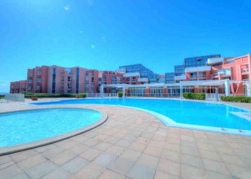 une grande piscine avec des bâtiments en arrière-plan dans l'établissement Cap corniche Sète front de mer parking wifi, à Sète