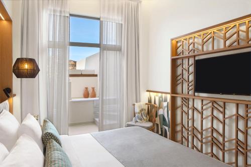 a bedroom with a bed and a flat screen tv at Mirabello Bay Luxury Resort in Agios Nikolaos