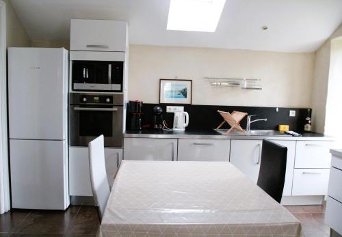 a kitchen with a table and a white refrigerator at L'Appartement du port, vue mer, jardin et parking in Roscoff