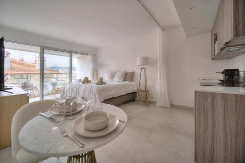 une chambre blanche avec un lit et une table avec de la vaisselle dessus dans l'établissement STUDIO SUPERBE, NEUF et MODERNE A0B196, à Cannes