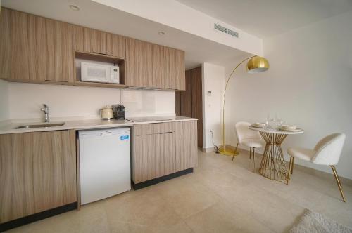 une cuisine avec un réfrigérateur blanc et une table dans l'établissement STUDIO SUPERBE, NEUF et MODERNE A0B196, à Cannes