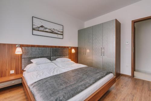 a bedroom with a large bed and a tv on the wall at BIRGÉS Villapark Apartments in Balatonfüred
