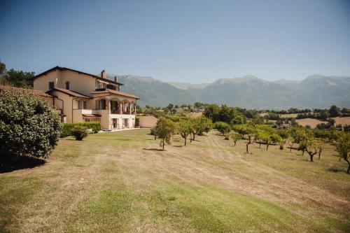 a house in a field with trees and mountains in the background at RELAIS COLLE BUONO in Alvito