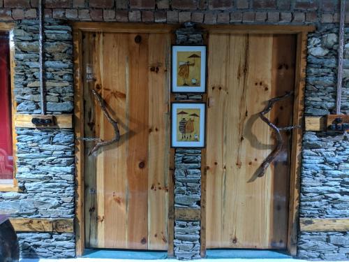 a wooden door on a stone building with pictures on it at Wild orchid trail cottages in Jhatingr