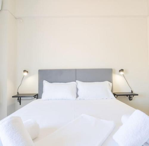 a bedroom with a white bed with two lamps at Urban Breeze Chalkida in Chalkida
