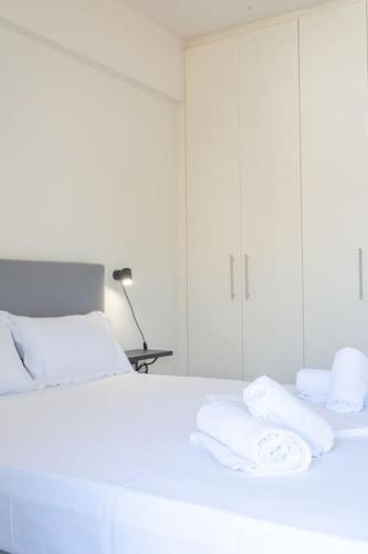 a white bedroom with a bed with towels on it at Urban Breeze Chalkida in Chalkida