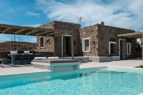 a villa with a swimming pool in front of a house at Onos Luxury Villas Kythnos in Kithnos