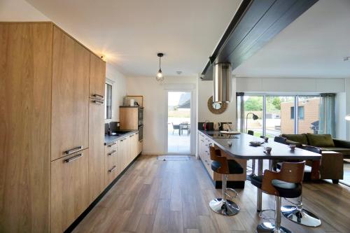 une cuisine avec des armoires en bois et une table et des chaises dans l'établissement Villa Sophie - 500m de la mer - jacuzzi, à Moëlan-sur-Mer