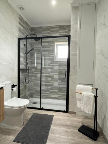 a bathroom with a toilet and a glass shower at Villa Garcia in Terras de Bouro