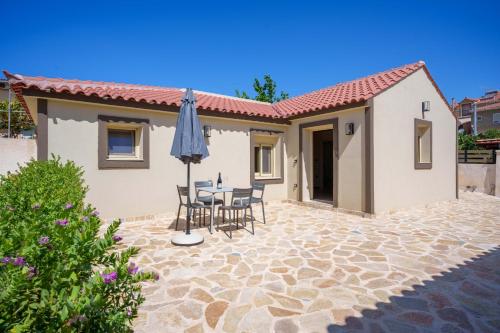 a patio with a table and chairs and an umbrella at Kosmas Villas in Skala Kefalonias