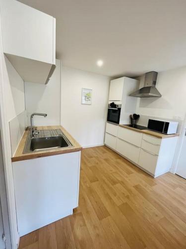 une cuisine avec des armoires blanches et un évier dans l'établissement Appartement Le Romy Vue Montagne, à Mont-Dore