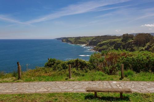 a bench sitting on top of a hill overlooking the ocean at La Colina in Gijón