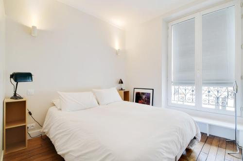 une chambre blanche avec un grand lit et une fenêtre dans l'établissement GuestReady - Parisian elegance in the 19th Arr., à Paris