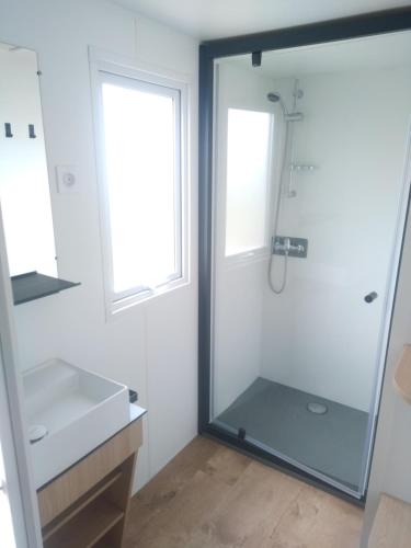 une salle de bain avec une douche en verre et un lavabo dans l'établissement Camping Les Voiles, à Flocques