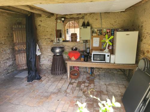 a kitchen with a counter with a microwave and a refrigerator at Les cabanes du veau in Daumeray