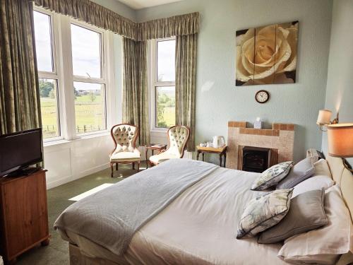 a bedroom with a bed and a fireplace and windows at Dunns Houses Farmhouse B&B in Otterburn