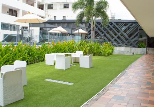 a patio with white chairs and grass at Hotel CasaBlanca Cucuta in Cúcuta
