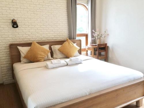 a bedroom with a large white bed with two pillows at Circle de Montana Khaoyai - เซอร์เคิล ดิ มอนทาน่า เขาใหญ่ in Ban Rai
