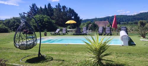 - une piscine avec des chaises, un parasol et un palmier dans l'établissement Propriété avec piscine de 2 à 9 personnes, Gîte De Saint Donat,, à La Roque-Gageac
