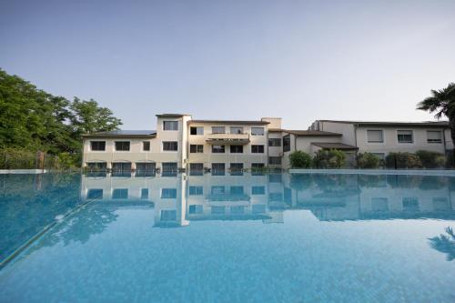une grande piscine d'eau devant un bâtiment dans l'établissement Logis Hotel Restaurant SPA Les Oliviers, à Loriol-sur-Drôme