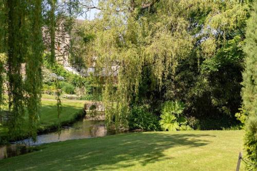 a park with a river and trees and grass at Badgers Den in Blockley