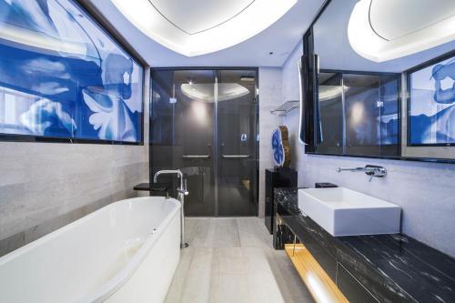 La salle de bains est pourvue d'une baignoire blanche et d'un lavabo. dans l'établissement Sofitel Nanjing Galaxy, à Nankin