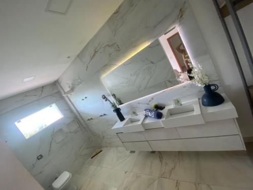an attic bathroom with white marble walls and a window at Sobrado piscina bem localizado 5 min do Flamboyant in Goiânia