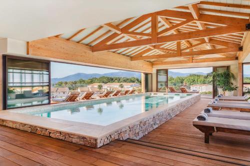 an indoor swimming pool with chairs and a large window at Relais et Châteaux Thalasso & Spa Ile de la Lagune in Saint-Cyprien