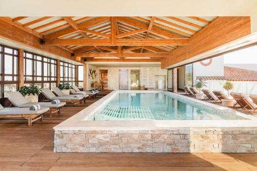 a pool in a house with chairs and a table at Relais et Châteaux Thalasso & Spa Ile de la Lagune in Saint-Cyprien
