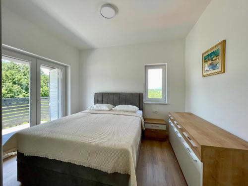 a bedroom with a bed and a dresser and windows at Villa Mirta in Zmijavci