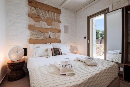 a bedroom with a large white bed with towels on it at Onos Luxury Villas Kythnos in Kithnos