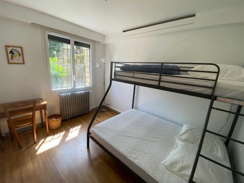 a bedroom with two bunk beds and a desk and a window at Appartement dans Villa in Ouistreham