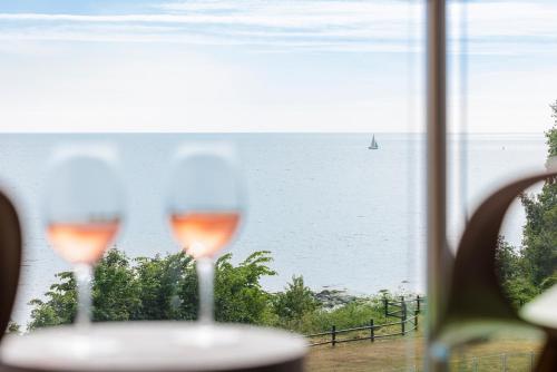 two wine glasses sitting on a table with a view of the ocean at Fredensborg Badehotel in Rønne