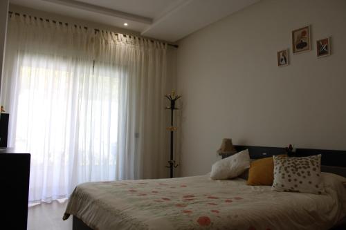 a bedroom with a bed and a large window at Très Joli rez-de-jardin à 2 min de la plage Les Sablettes in Mohammedia