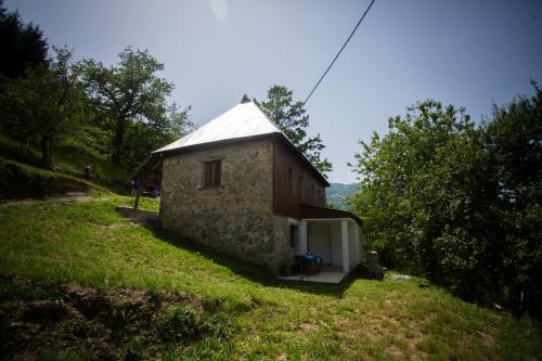 a small stone house on a grassy hill at Ethno guesthouse Tara in Mojkovac