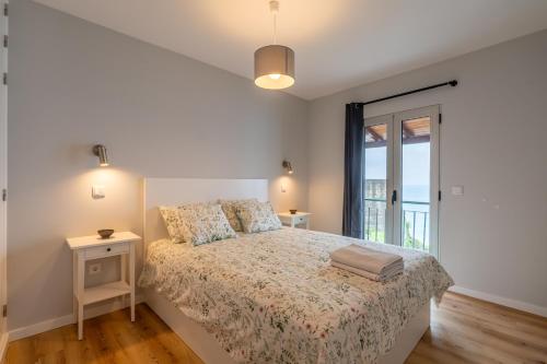 a white bedroom with a bed and a window at Casas das Hortas, Apartamento Vista Mar in Seixal
