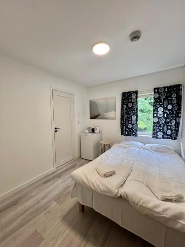 a white bedroom with a large bed and a window at Trolltunga Studios in Odda