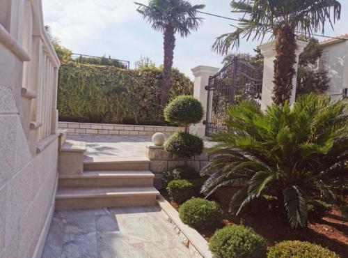 a house with stairs and palm trees in a yard at Apartments White House in Supetar