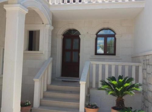 a white house with stairs and a door at Apartments White House in Supetar