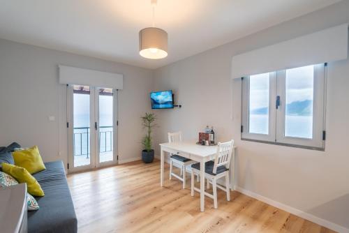 a living room with a white table and chairs at Casas das Hortas, Apartamento Vista Mar in Seixal