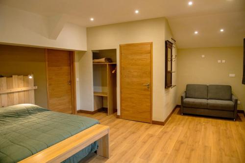a bedroom with a bed and a couch and a chair at La ferme de Berlioz in La Côte-Saint-André