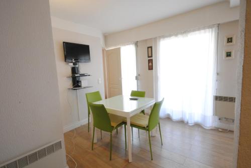 une salle à manger avec une table blanche et des chaises vertes dans l'établissement superbe appartement tout confort beg4012, à Cannes