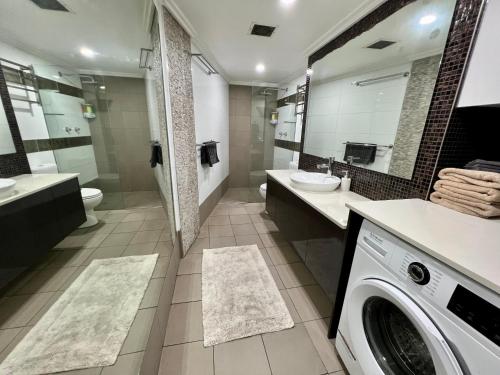 a bathroom with a washing machine and a washer and dryer at Kingsleigh Apartments Sydney in Sydney