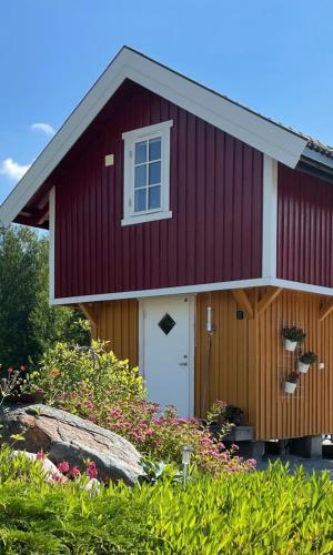 a red house with a white door and a window at Unik overnatting i Stabbur/Minihus in Lunde
