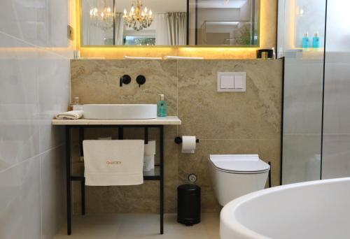 a bathroom with a sink and a toilet and a mirror at Garden Luxury Rooms in Split